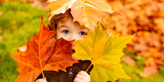Kind mit Blättern im Herbst