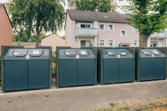 Behälterstandplatz Behälter mehrerer Abfallfraktionen stehen nebeneinander vor einem Wohnhaus