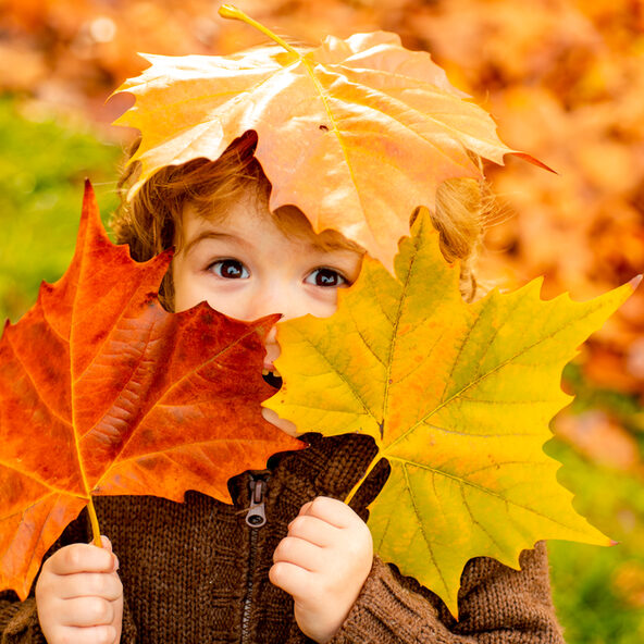 Kind mit Blättern im Herbst