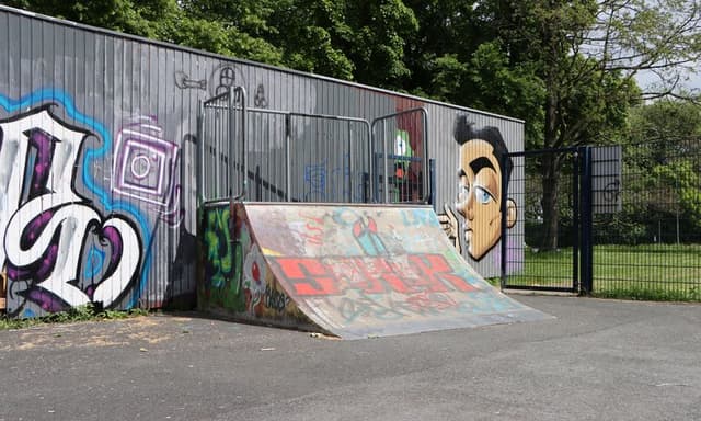 Rampe in einem Skatepark, im Hintergrund Graffitti
