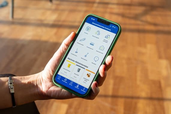 WBD App Ansicht auf einen Smartphone, das in einer Hand gehalten wird.